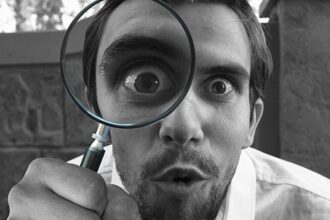 Una persona con una lupa observando algo detalladamente.