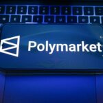 In this photo illustration, a Polymarket logo is displayed on a smartphone on top of a laptop.