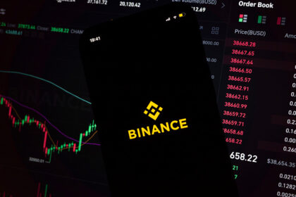 In this photo illustration, an iPhone displays the app and logo of popular cryptocurrency exchange platform Binance, with the desktop version in the background displaying market trends and exchange rates for cryptocurrency Bitcoin on 8th March, 2022 in Leeds, United Kingdom. (photo by Daniel Harvey Gonzalez/In Pictures via Getty Images)